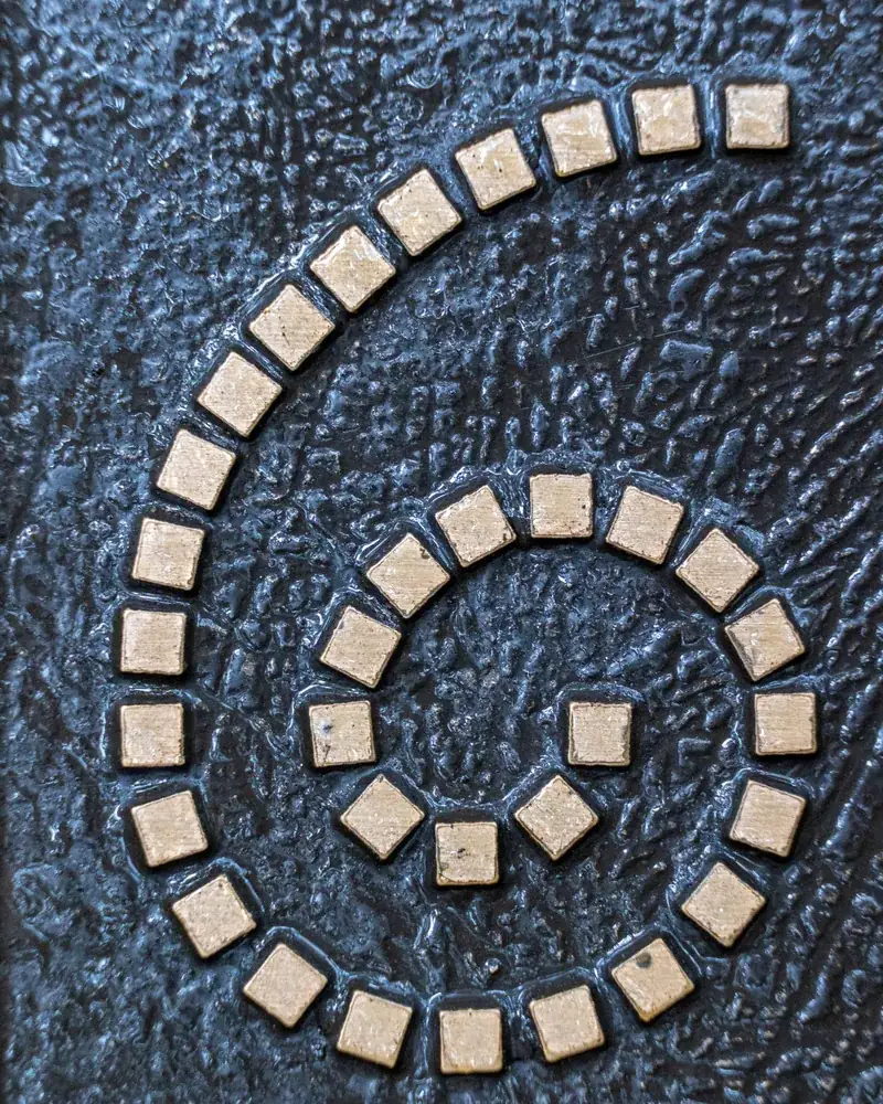 Detalle de teselas cuadradas colocadas en espiral con juntas anchas y regulares